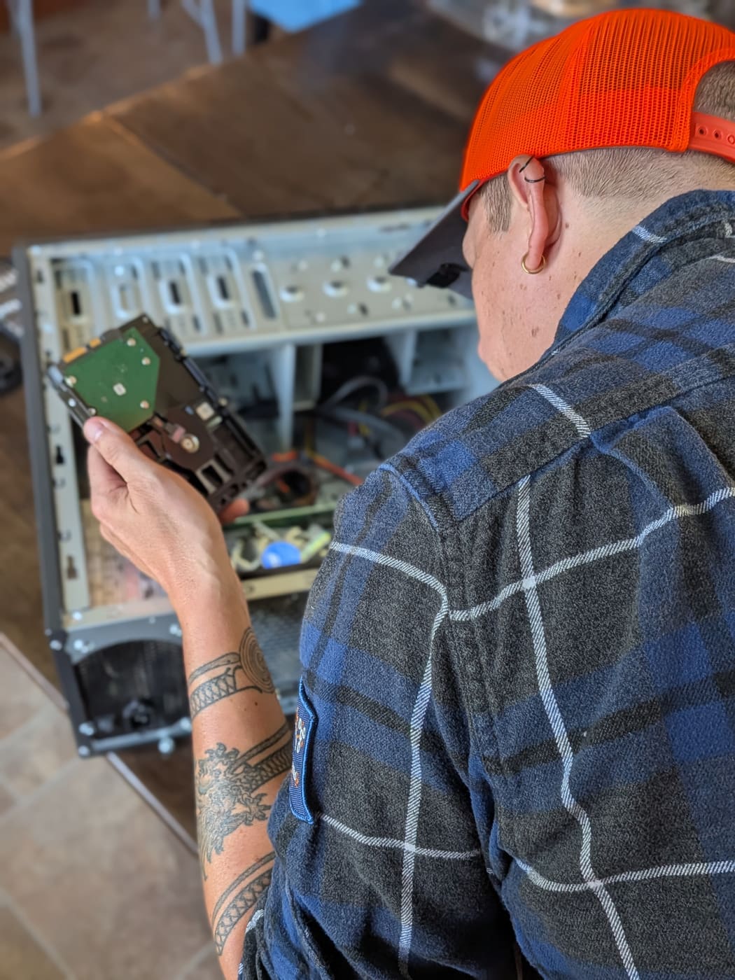 A Tomah Tech Hero technician inspecting a hard drive over an open desktop computer